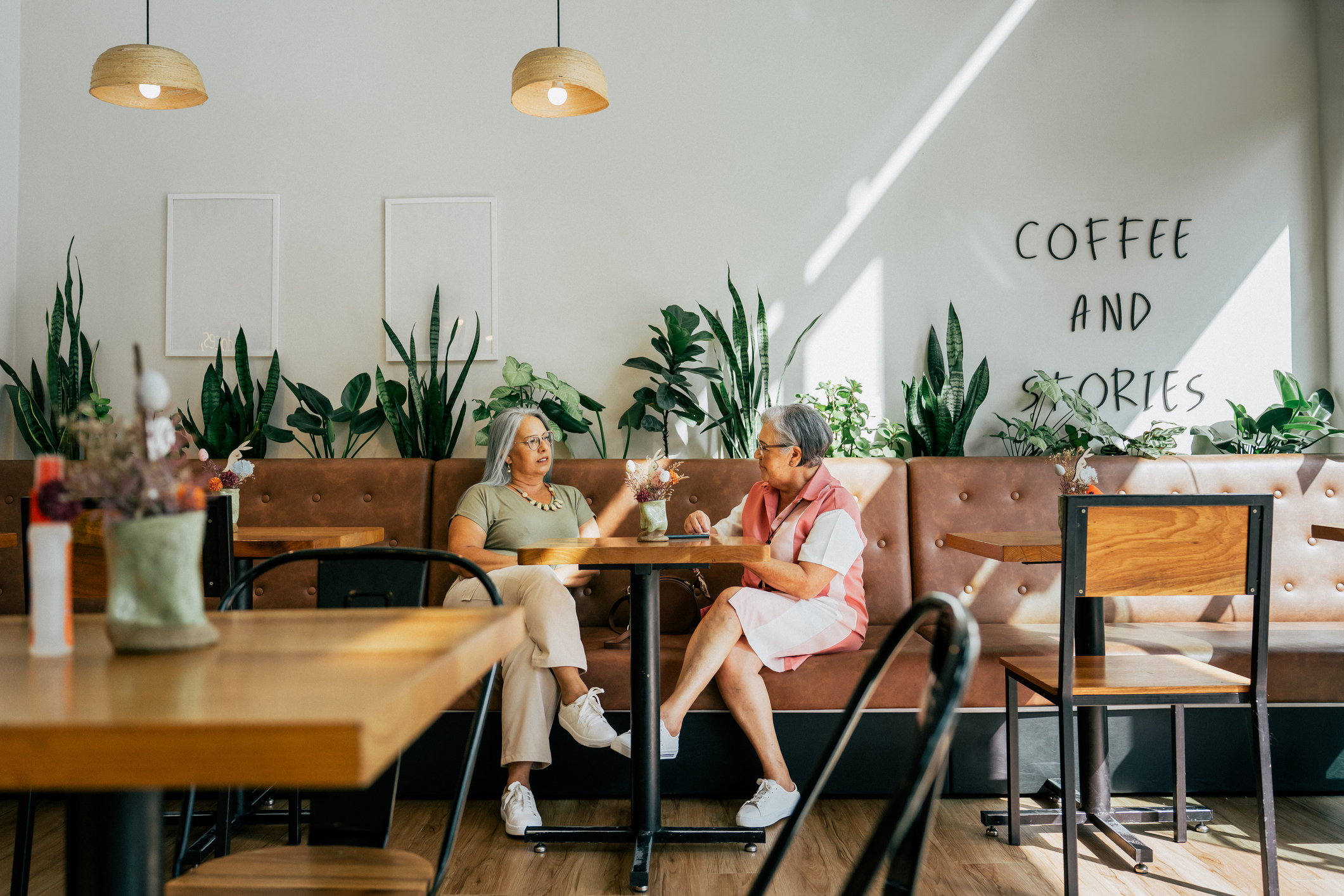 Two female friends chatting while drinking coffee in a cafe Bistro Senior Living