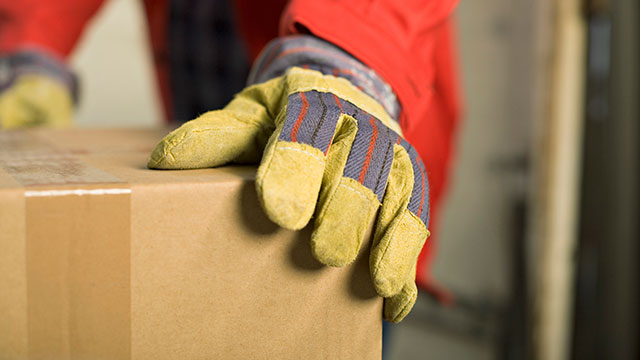 person holding shipping box with gloves