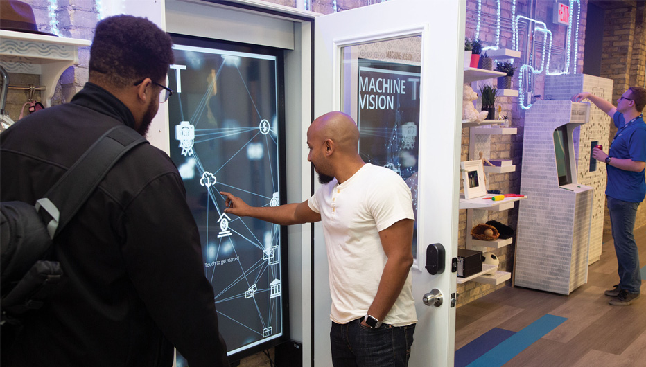 Two people interacting with wall mounted touchscreen