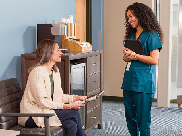 female young nurse and female young patient speaking in waiting room of clinic