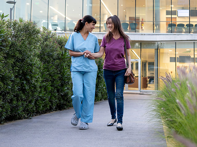 female nurse and patient walking outside outpatient hospital