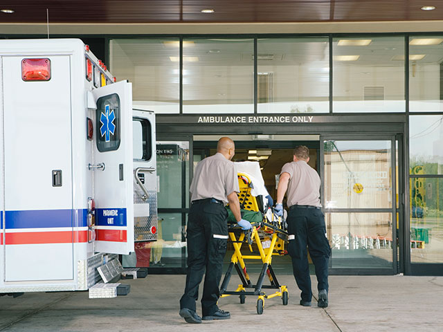 Paramedics taking patient on stretcher from ambulance to hospital