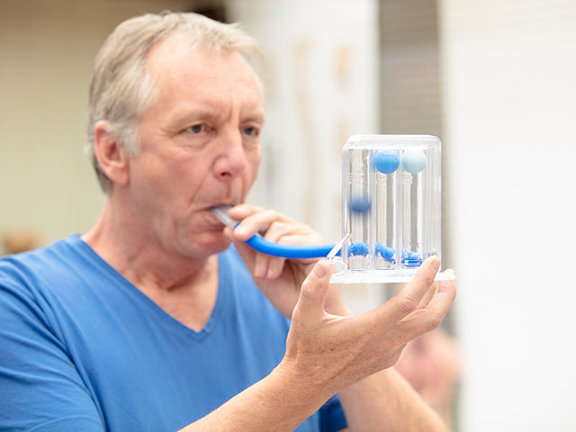 A male person, performing a simple lung function test by using a triflow