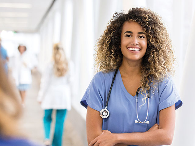 female nurse in hospital hallway smiling at camera