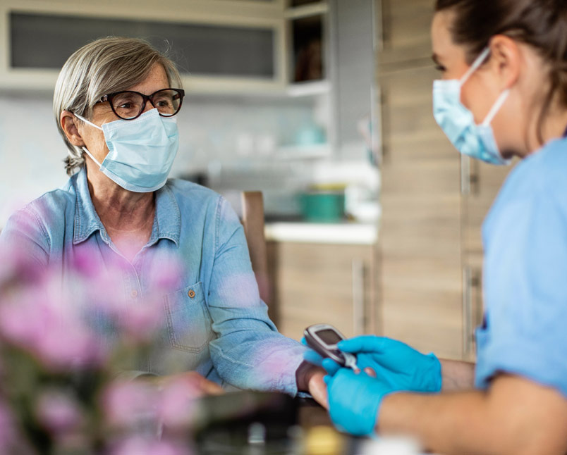 long term care nurse talking to senior with ppe mask