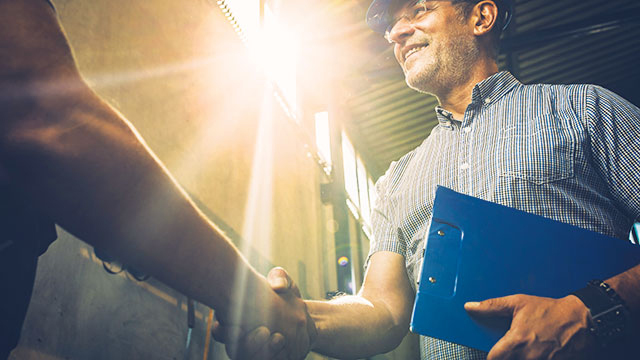 man with clipboard and hard hat shaking hands