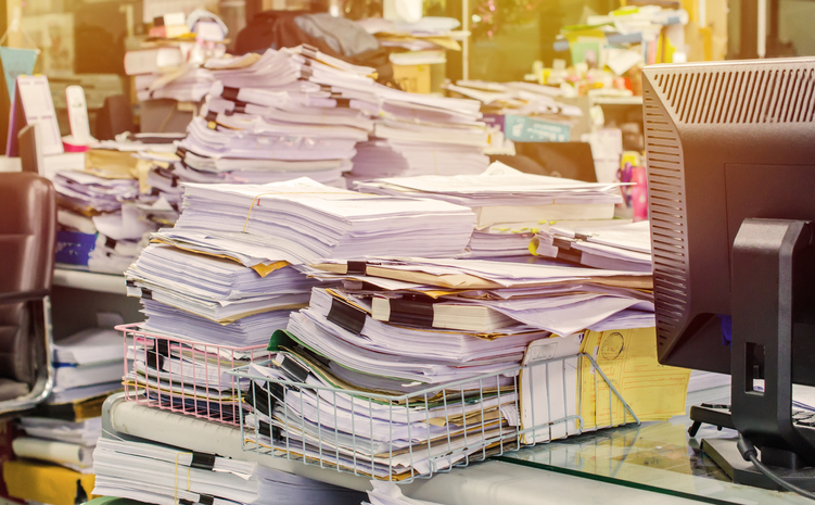 stacked binders and paperwork on messy desk why cmms documentation management